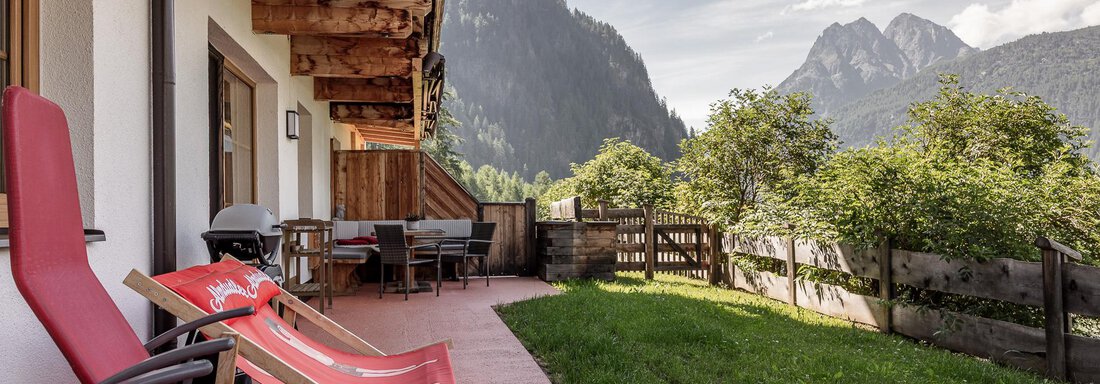 A cozy terrace with red loungers and a view of the mountains. The surroundings are green and inviting. - MYALPS Himmelreich - Längenfeld