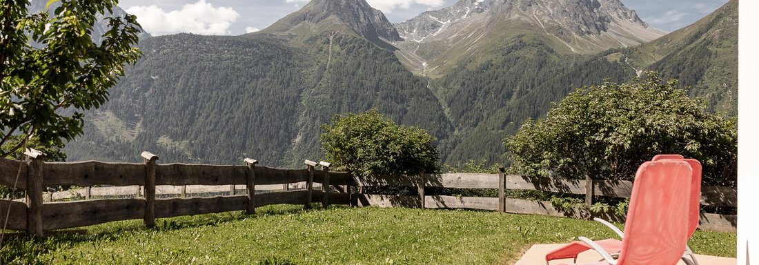 A relaxed terrace with lounge chairs and a view of majestic mountains. The landscape is green and inviting, perfect for a quiet day outdoors. - MYALPS Himmelreich - Längenfeld