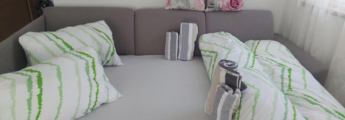 Ein gemütliches Bett mit gestreiften Kissen und einer Decke in hellen Farben. Die Atmosphäre wirkt einladend und frisch. - Apart Stefan - Niederthai