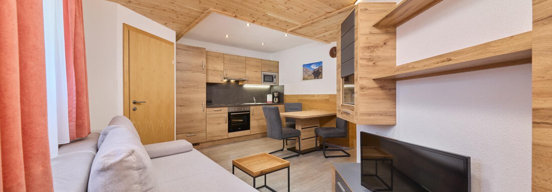 A modern apartment with wooden elements and a cozy decor. It features a lounge area, a dining table, and an integrated kitchen. - Appartement Lea - Niederthai