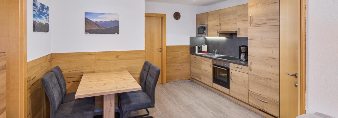 A cozy kitchen with a wooden dining area. The walls are painted light and there are modern kitchen appliances. - Appartement Lea - Niederthai