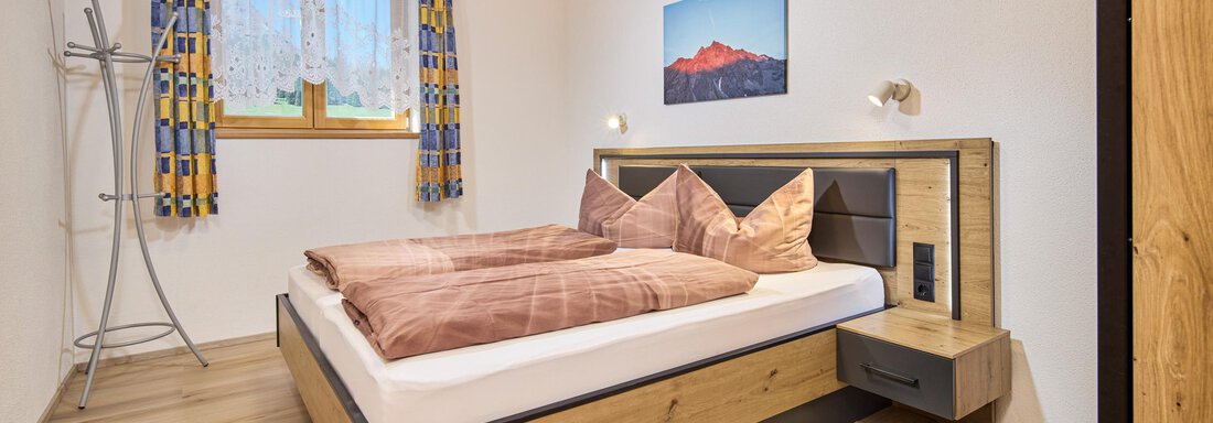 A cozy bedroom with a large bed and modern furniture.  
Bright colors and a window create a pleasant atmosphere. - Appartement Lea - Niederthai