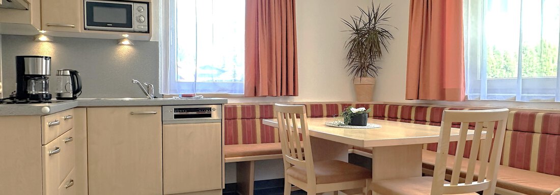 Voll ausgestattete Wohnküche mit hellen Holzmöbeln und Essbereich. Große Fenster lassen viel Tageslicht hinein. - Appartement Leiter Niki - Niederthai