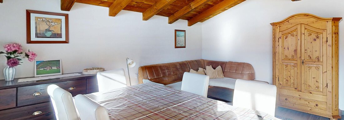 Wohnküche Bergzauber III A cozy dining area with a large table and chairs. The room has a bright atmosphere with wooden beams and a rustic cabinet. - Gipfelblick Appartements - Niederthai