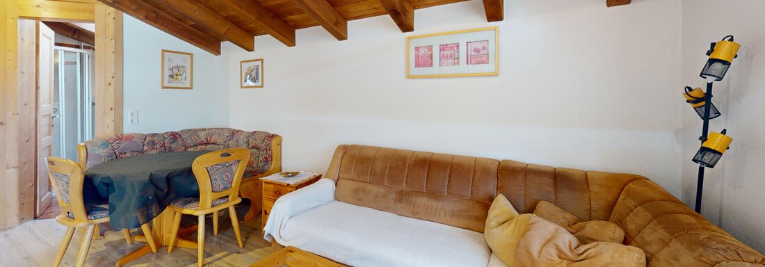 Ein gemütlicher Wohnraum mit Holzdecken und einem Sofa. Es gibt auch einen Tisch und einige Dekorationen an den Wänden. - Gipfelblick Appartements - Niederthai