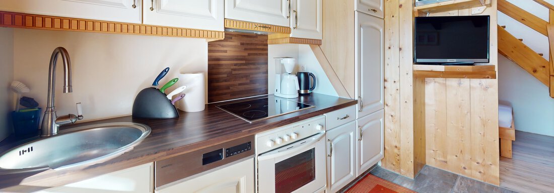 Küche Alpenglühen A modern kitchen with wooden details and a functional layout. The room is bright and inviting. - Gipfelblick Appartements - Niederthai