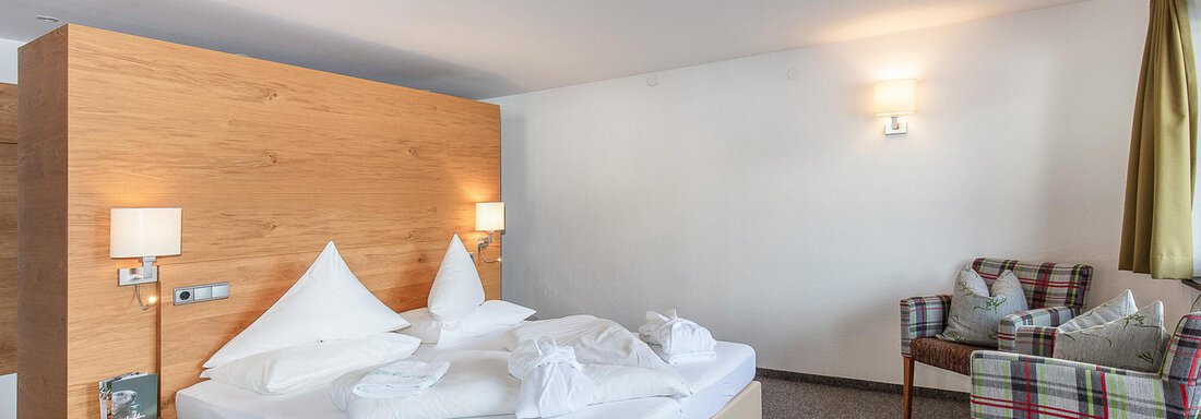 Ein modernes Schlafzimmer mit einem großen Bett und gemütlicher Dekoration. Die Wände sind hell und der Raum wirkt einladend. - Hotel Falknerhof, am Ursprung - Niederthai