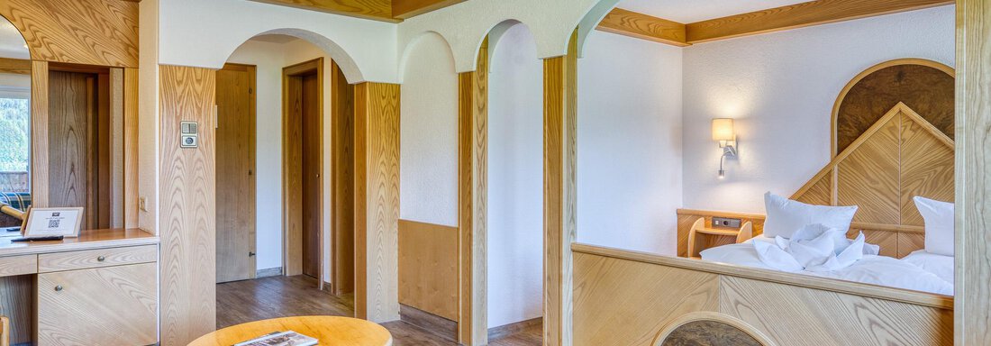 Ein gemütliches Zimmer mit Holzmöbeln und einem Doppelbett. Der Raum hat große Fenster und einen einladenden Sitzbereich. - Hotel Falknerhof, am Ursprung - Niederthai