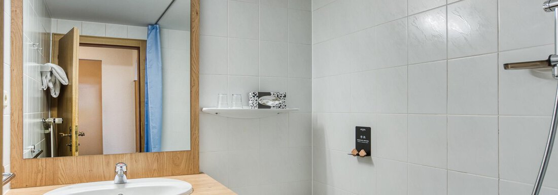 Ein modernes Badezimmer mit einer Badewanne und einem Waschbecken aus Holz. Helle Fliesen und ein großer Spiegel sorgen für eine freundliche Atmosphäre. - Hotel Falknerhof, am Ursprung - Niederthai