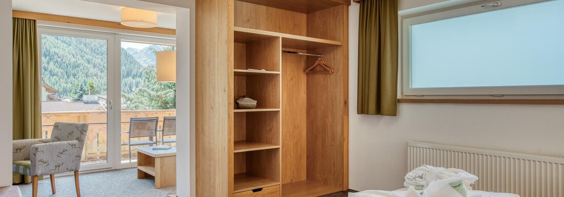 Ein komfortables Hotelzimmer mit einem großen Fenster und Blick auf die Berge. Es gibt ein Holzregal und ein gemütliches Bett mit frischen Handtüchern. - Hotel Falknerhof, am Ursprung - Niederthai