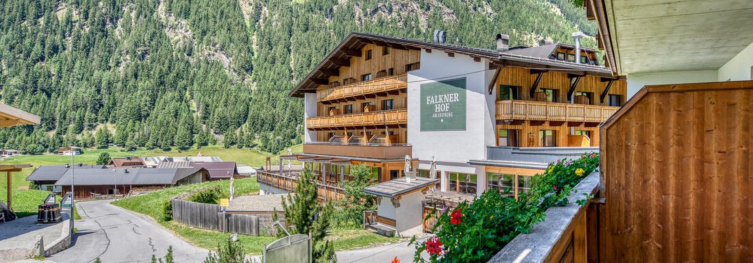 Ein malerisches Hotel in den Bergen, umgeben von grüner Natur. Die Umgebung zeigt die sanften Hügel und Bäume der Alpen. - Hotel Falknerhof, am Ursprung - Niederthai