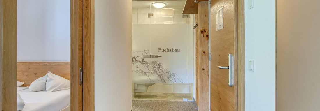 Ein heller Flur mit Holzdetails und einem modernen Badezimmer. Im Hintergrund ist ein gemütliches Schlafzimmer sichtbar. - Hotel Falknerhof, am Ursprung - Niederthai