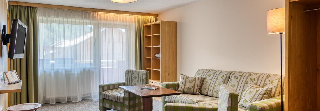Ein gemütliches Wohnzimmer mit einem Sofa und Sessel im klassischen Design. Große Fenster sorgen für viel natürliches Licht. - Hotel Falknerhof, am Ursprung - Niederthai