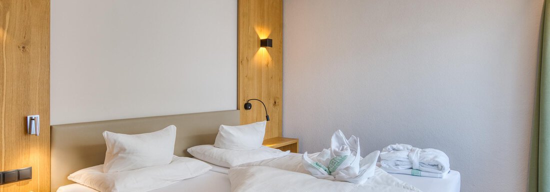 Ein modernes Hotelzimmer mit zwei Betten und frischen Handtüchern. Die Wände sind hell, und das Zimmer wirkt ruhig und einladend. - Hotel Falknerhof, am Ursprung - Niederthai