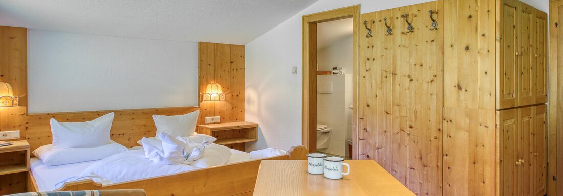 Ein gemütliches Hotelzimmer mit Holzverkleidung und zwei Betten. Der Raum verfügt über einen Tisch und einen integrierten Kleiderschrank. - Hotel Falknerhof, am Ursprung - Niederthai