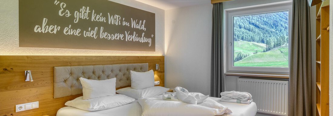 Ein gemütliches Schlafzimmer mit einem Doppelbett und frischen Handtüchern. Das Fenster bietet einen Blick auf die grüne Landschaft draußen. - Hotel Falknerhof, am Ursprung - Niederthai