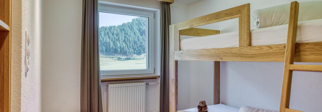 Ein gemütliches Zimmer mit einem Etagenbett und Blick auf die Berge. Der Raum ist hell und freundlich gestaltet. - Hotel Falknerhof, am Ursprung - Niederthai