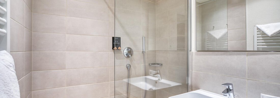 Ein modernes Badezimmer mit einer begehbaren Dusche und einem stilvollen Waschbecken. Die Wände sind in neutralen Farbtönen gehalten. - Hotel Falknerhof, am Ursprung - Niederthai