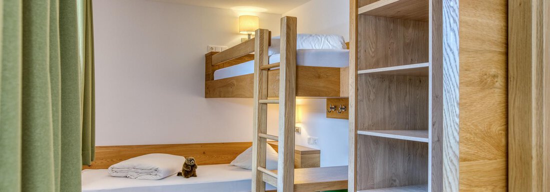 Ein gemütliches Zimmer mit einem Etagenbett und einem Einzelbett. Es gibt einen Regal und einen grünen Stuhl. - Hotel Falknerhof, am Ursprung - Niederthai