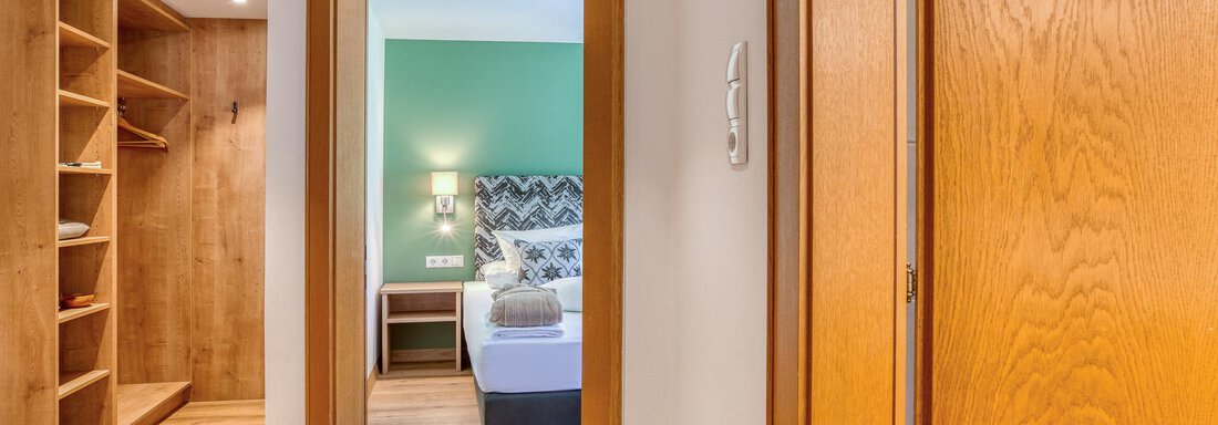 Ein heller Flur mit Holzregalen und einem offenen Zugang zu einem gemütlichen Schlafzimmer. Die Wände sind in sanften Farben gehalten und sorgen für eine einladende Atmosphäre. - Hotel Falknerhof, am Ursprung - Niederthai