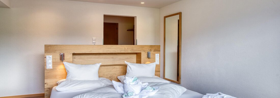 Ein modernes Schlafzimmer mit einem großen Bett und hellen Decken. Die Wände sind schlicht und der Raum ist gut beleuchtet. - Hotel Falknerhof, am Ursprung - Niederthai