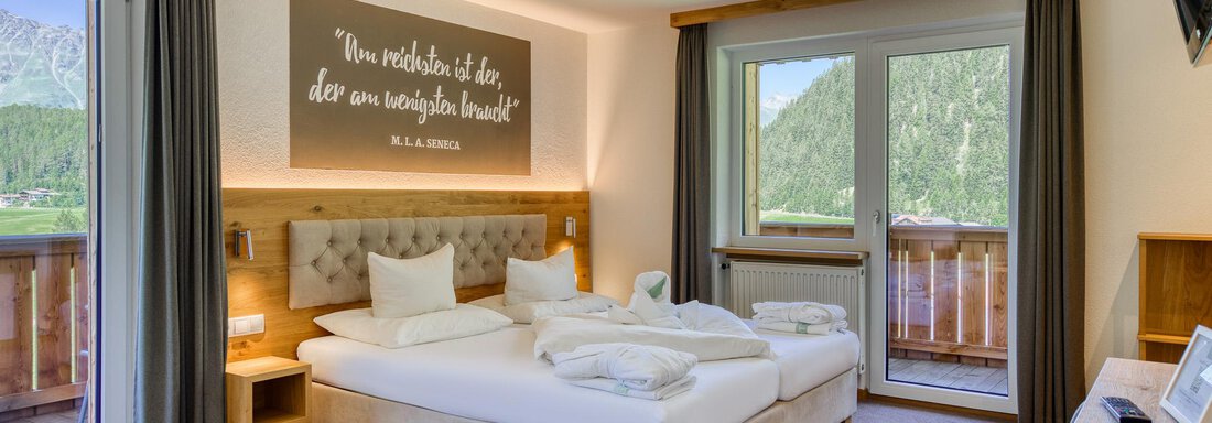 Ein modernes Hotelzimmer mit einem Doppelbett, einem Fernseher und großen Fenstern, die auf eine schöne Aussicht blicken. Die Wände sind hell und geschmackvoll dekoriert. - Hotel Falknerhof, am Ursprung - Niederthai