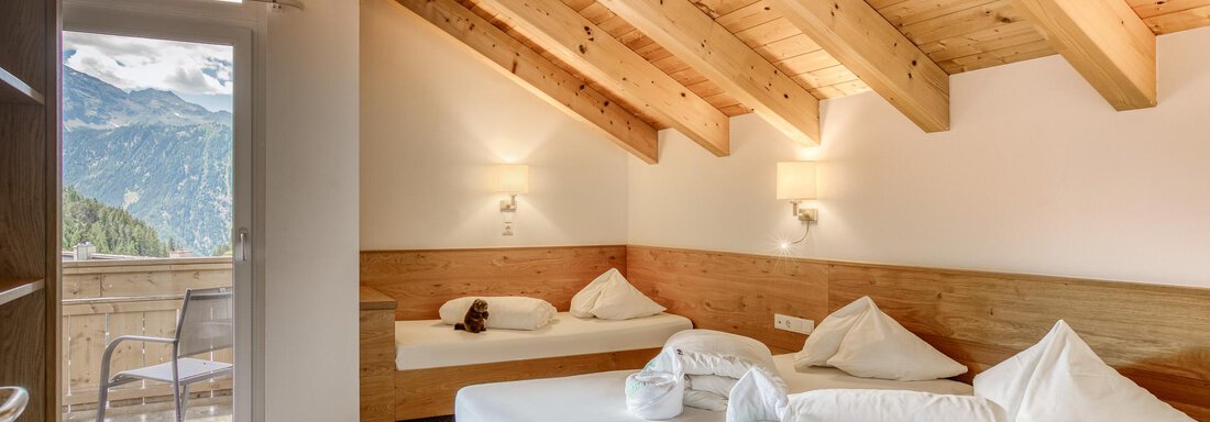 Ein modernes Zimmer mit Holzdecke und gemütlichen Betten. Es gibt einen Balkon mit Blick auf die Berge. - Hotel Falknerhof, am Ursprung - Niederthai