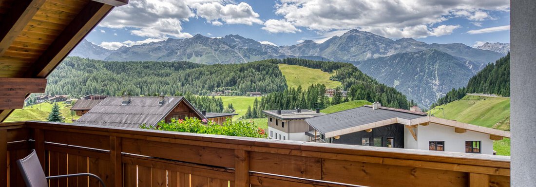 Ein Blick von einem Balkon auf eine malerische Berglandschaft mit grünen Wiesen und hohen Bergen. Der Himmel ist klar mit einigen Wolken. - Hotel Falknerhof, am Ursprung - Niederthai