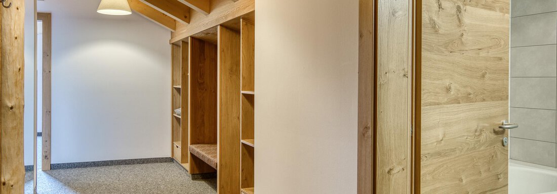 Ein heller Flur mit Holzdecken und Regalen. Die Wände sind neutral, und es gibt einen Raum mit einer Tür. - Hotel Falknerhof, am Ursprung - Niederthai