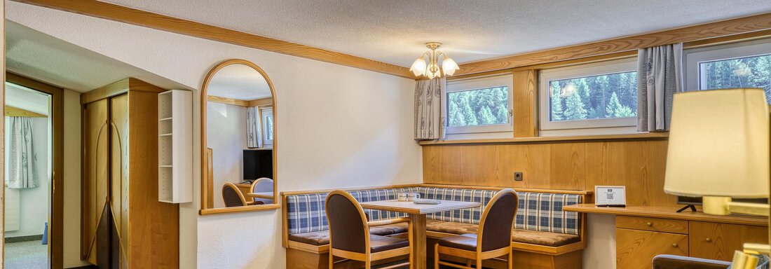 Ein gemütlicher Wohnraum mit einem Esstisch und Stühlen. Die Einrichtung ist hell und freundlich, mit Fenstern, die natürliches Licht hereinlassen. - Hotel Falknerhof, am Ursprung - Niederthai