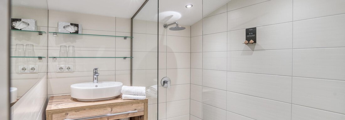 Ein modernes Badezimmer mit klaren Linien und einem stilvollen Waschbecken. Helle Fliesen und eine Glasdusche schaffen ein luftiges Ambiente. - Hotel Falknerhof, am Ursprung - Niederthai