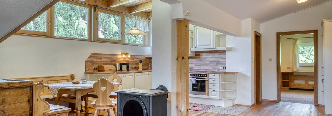 Ein gemütlicher Wohnraum mit Holzfußboden, einer modernen Küche und einem Esstisch. Große Fenster sorgen für viel Tageslicht und schaffen eine einladende Atmosphäre. - Hotel Falknerhof, am Ursprung - Niederthai
