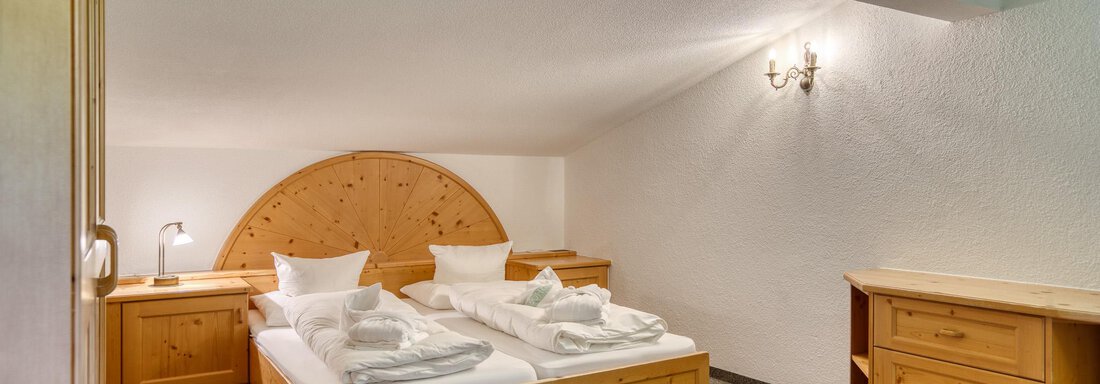 Ein gemütliches Schlafzimmer mit einem Doppelbett und Holzmöbeln. Die Raumgestaltung ist einfach und einladend. - Hotel Falknerhof, am Ursprung - Niederthai