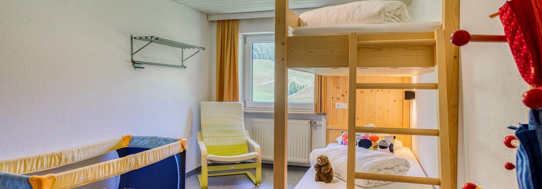 Ein gemütliches Kinderzimmer mit einem Etagenbett und einem Reisebett. Helle Wände und ein Fenster sorgen für eine freundliche Atmosphäre. - Hotel Falknerhof, am Ursprung - Niederthai