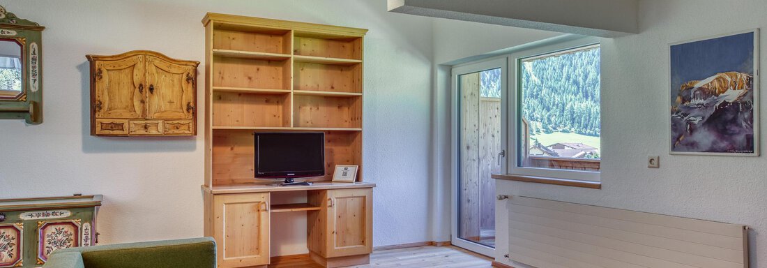 Ein gemütliches Wohnzimmer mit grünen Sofas und einem Holztisch. Eine große Fensterfront bietet einen Blick auf die Natur. - Hotel Falknerhof, am Ursprung - Niederthai