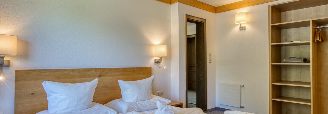 Ein gemütliches Schlafzimmer mit einem großen Doppelbett und hellen Wänden. Der Raum verfügt über einen Kleiderschrank und sanfte Beleuchtung. - Hotel Falknerhof, am Ursprung - Niederthai