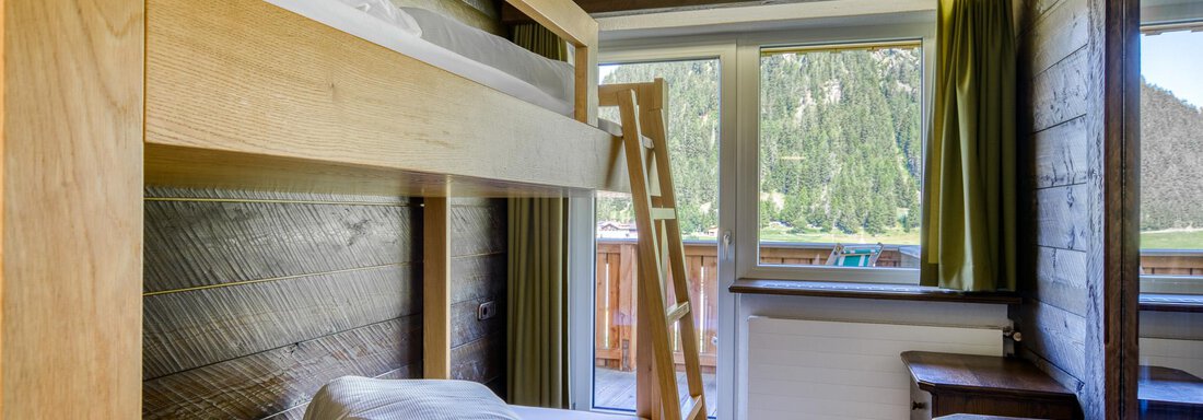Ein einfaches Zimmer mit einem Hochbett und einem Tisch. Große Fenster bieten einen Blick auf die umliegende Natur. - Hotel Falknerhof, am Ursprung - Niederthai