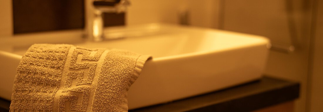 Ein modernes Badezimmer mit einem eleganten Waschbecken und einem Handtuch. Die warmen Farben sorgen für eine gemütliche Atmosphäre. - Sonnenhof - Niederthai