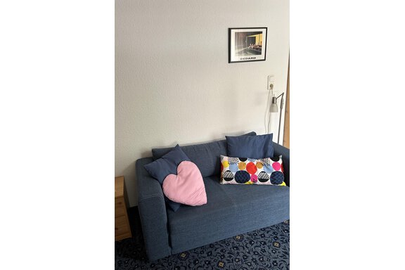 A cozy sofa with colorful cushions in a bright room. A framed picture hangs on the wall. - App. Diamant Obergurgl - Obergurgl 