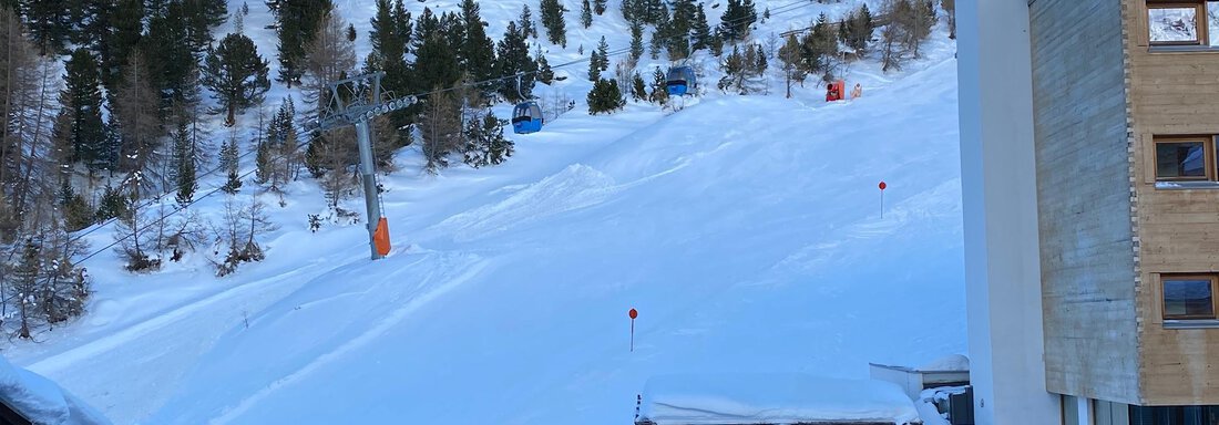 A snow-covered slope with some ski lifts. In the background, green trees and mountain forest are visible. - App. Diamant Obergurgl - Obergurgl 