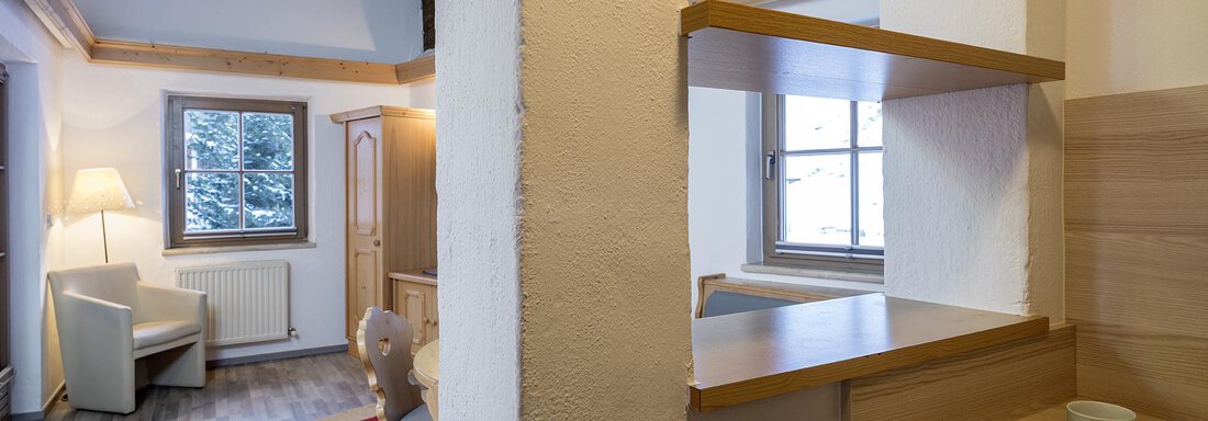 A bright, cozy room with wooden ceilings and a view from the window. On the right side, teacups and a small kitchenette are visible. - Appartementhaus Schalfblick - Obergurgl 