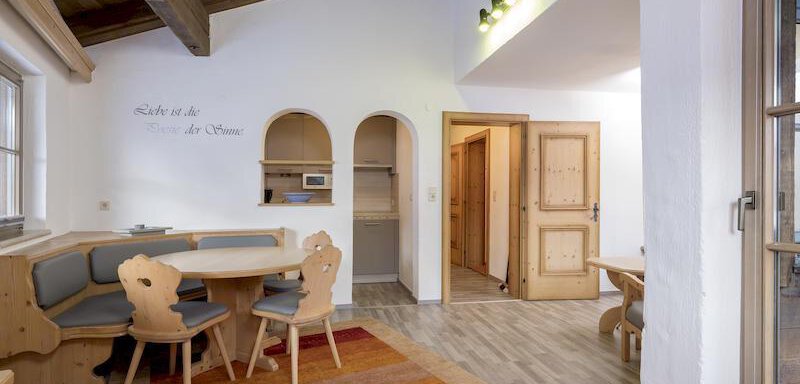 Wohnschlafraum A cozy living space with wooden furniture and large windows. The floor is covered with a colorful rug that creates an inviting atmosphere. - Appartementhaus Schalfblick - Obergurgl