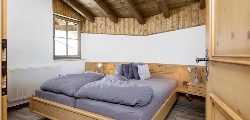 A cozy bedroom with a wooden frame bed and a warm wooden ceiling. The atmosphere is inviting and friendly. - Appartementhaus Schalfblick - Obergurgl 