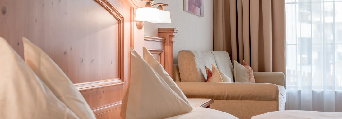 A cozy hotel room with a comfortable bed and a sofa. Large windows let in plenty of light and create an inviting atmosphere. - Ferienwohnung de Luxe Alpenresidenz am Mühlbach - Obergurgl 