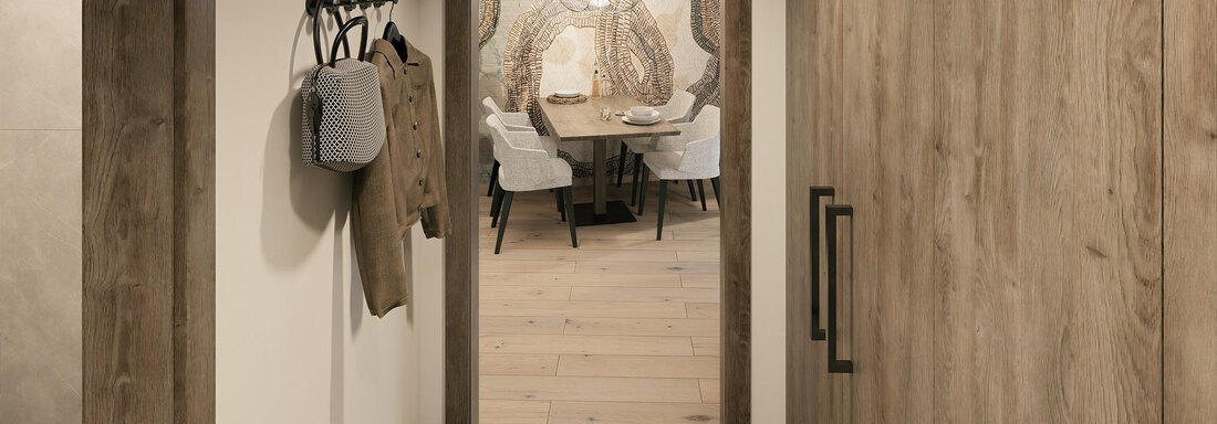 A modern entrance area with wood details and a coat rack. In the background, an inviting dining area with a stylish table and chairs can be seen. - Ferienwohnung de Luxe Alpenresidenz am Mühlbach - Obergurgl 