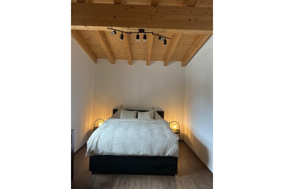 A modern bedroom with a large bed and two bedside lamps. The wooden ceiling creates a cozy atmosphere. - Forest Chalet - Obergurgl 