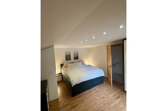 A cozy bedroom with a large bed and indirect lighting. The room has light walls and a wooden floor that creates a warm atmosphere. - Forest Chalet - Obergurgl 