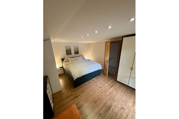 A cozy bedroom with a large bed and wooden floor. The room is brightly lit and arranged in a friendly manner. - Forest Chalet - Obergurgl 
