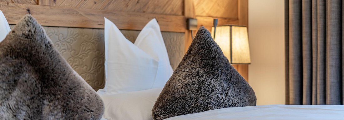 A cozy hotel room view with two beds and soft pillows. Behind the bed is a warm wood paneling and a gentle light. - Gletscherblick - Serviced Apartments - Obergurgl 