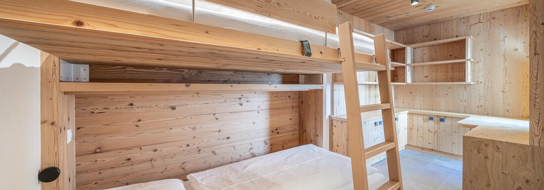 A cozy room with wooden loft beds. The walls are also made of wood, creating a warm atmosphere. - Gletscherblick - Serviced Apartments - Obergurgl 